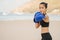 Athletic Asian girl on the beach in summer in a sports black suit leading a boxing training.