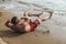 An athletic asian guy does bicycles crunches on the sand at the beach. Cardio workout, calisthenics or Abdominal training