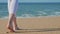 Athletic barefooted woman walking on the beach, sea waves on background
