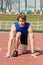 Athletic bearded man with muscular body stretching on running track