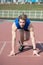 Athletic bearded man with muscular body stretching on running track