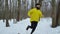 Athletic bearded man running in forest on snow covered path on winter day