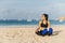 Athletic beautiful Asian girl sitting on the sand after a boxing workout and drinks water
