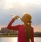 Athletic beautiful sports woman is drinking pure water from the bottle refreshing herself after running on sunny bright