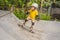 Athletic boy in helmet and knee pads learns to skateboard with in a skate park. Children education, sports