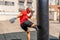 Athletic caucasian man exercising with black punching bag, having workout at street gym yard. Sports and health concept
