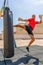 Athletic caucasian man exercising with black punching bag, having workout at street gym yard. Sports and health concept