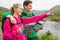 Athletic couple in hooded jumpers on a hike holding map