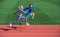 Athletic couple of sprinters run on running track at stadium, energy