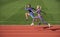athletic couple of sprinters run on running track at stadium, energy