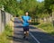 Athletic european man in sportswear jogging on road in green park on beautiful summer day