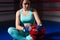 Athletic female boxer sitting and holding helmet