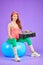 Athletic female dancer sits on fit ball with portable cassette player on knees