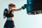 Athletic female fighter boxing on punching bag of tires in studio in neon light. Mixed martial arts poster