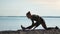 Athletic female stretching leg sitting on mat during workout at seashore. Shot with RED camera in 4K