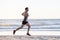 Athletic fit and strong runner man training on Summer sunset beach in sea shore running and fitness workout in sport and healthy l