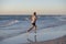 Athletic fit and strong runner man training on Summer sunset beach in sea shore running and fitness workout in sport and healthy l