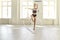 Athletic flexible girl gymnast performs exercises with a ribbon in a bright hall.