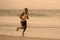 Athletic full body portrait of young attractive and fit black afro American man running on the beach doing Summer fitness jogging