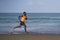 Athletic full body portrait of young attractive and fit black afro American man running on the beach doing Summer fitness jogging