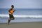 Athletic full body portrait of young attractive and fit black afro American man running on the beach doing Summer fitness jogging