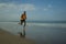 Athletic full body portrait of young attractive and fit black afro American man running on the beach doing Summer fitness jogging