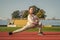 Athletic girl child do outward lunging during sports lesson at athletics stadium, physical education