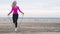 Athletic girl jumping rope on sand sea beach. Fitness in nature cloudy day