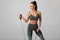 Athletic girl working out with resistance band on gray background. Fitness woman exercises with expander