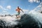 Athletic guy actively ride on the waves on surfboard against blue sky