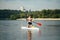 Athletic guy with a muscular body floats on a sup board on the river on the background of a beautiful landscape. Training on a