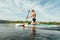 Athletic guy in sunglasses and a muscular body moves on the water on the sup board, actively rowing. Young man paddles on sup