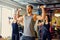 Athletic male and two slim female fitness models doing shoulder exercises with dumbbells.