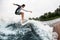 Athletic man active riding wave on surf style wakeboard and lifting up lot of splashes