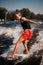 Athletic man balances on the wave on surf style wakeboard on sunny day