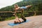 Athletic man balancing woman in his feet during acro yoga practice on terrace in mountains