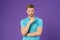 Athletic man in blue tshirt on violet background. Man with beard on unshaven face skin on purple backdrop. Fashion model with styl