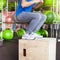 Athletic man with intense face and beard wearing a blue tee shirt performing crossfit box jump