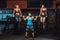 Athletic man lifts barbell with two girls as weight and girls hanging From barbell. barbell with two girls on it