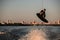 athletic man making trick in jump with wakeboard over splashing river. Summertime watersports activity