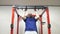 Athletic man performing strength exercise for upper-body on pull up bar at gym