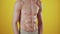 Athletic man poses on yellow background in studio, closeup off abs, front view. Fitness trainer demonstrates results of