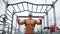 Athletic Man Pumps Up Muscles Doing Pull-Ups Open Sports Ground with Bare Torso