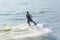 Athletic man swims on a water board holding on to a rope at sea