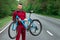 Athletic Man in a tracksuit holds a bicycle on his shoulders while standing on the road in the forest. The concept of a healthy