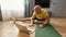 Athletic mature personal fitness conducting online training, sitting on yoga mat at home and showing sport exercises