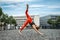 Athletic middle-aged woman doing gymnastics in the city square in the morning