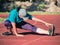 Athletic middle aged woman stretching on red  running track