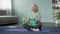 Athletic senior woman sitting on the floor and drinking water after workout