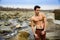 Athletic shirtless young man outdoor at river or water stream